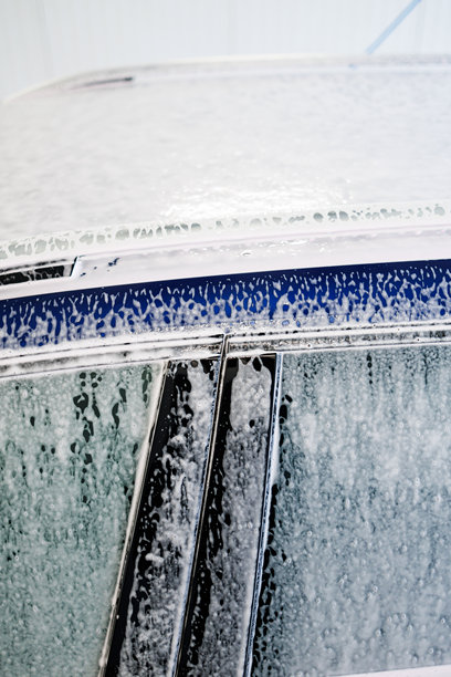 特写照片。带有厚泡沫的汽车零件。用于清洗脏污车辆的化学品。图片下载