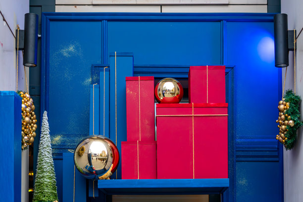 圣诞节橱窗装饰，带有红色礼品盒、金色饰球和一棵迷你圣诞树，背景为蓝色。图片下载