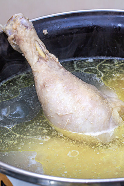 在家里的厨房用银色平底锅准备美味的鸡汤。是进一步制作汤的配料。清淡浓郁的肉汤有益于饮食。图片下载