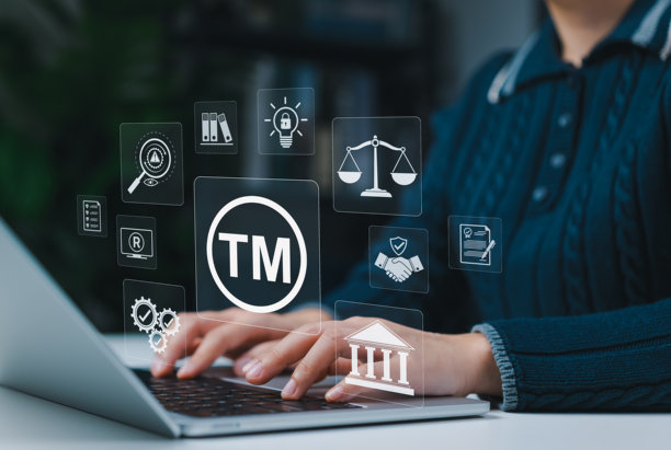 商标和知识产权保护概念，展示一名女性使用带有TM图标的笔记本电脑，并配有法律符号、法律协议和代表版权、专利和品牌所有权的安全性。图片下载
