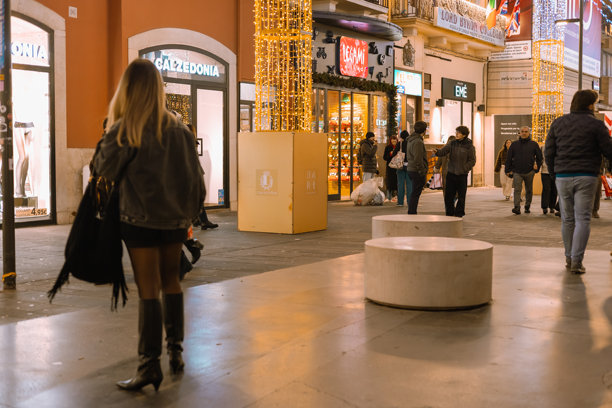 一位时尚年轻女子在意大利巴里的繁华商业街夜间行走，街边商店灯火通明，装饰着圣诞节日彩灯图片下载