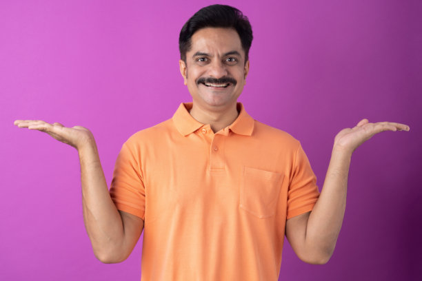 穿着橙色T恤的印度中年男子，孤立在紫色背景上的照片素材图片下载