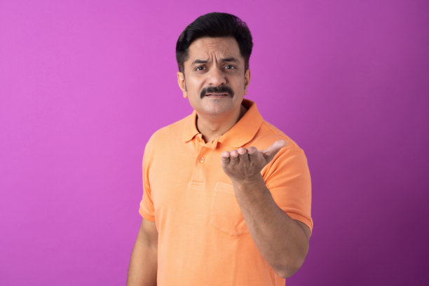 一名身穿橙色T恤的中年印度男子，在紫色背景下被孤立的肖像照片图片下载