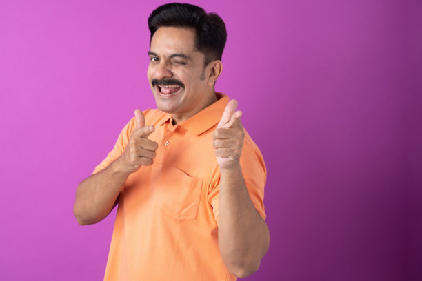 身穿橙色T恤的印度中年男子，孤立在紫色背景上的照片素材图片下载