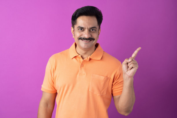 身穿橙色T恤的印度中年男子，在紫色背景上拍摄的素材照片图片下载