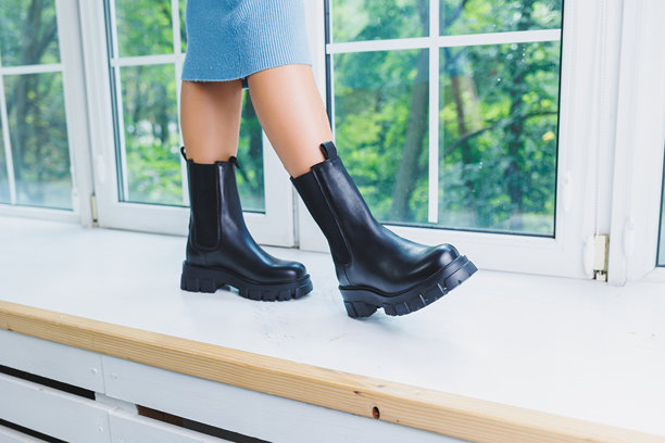 黑色女靴特写。真皮黑色靴子。穿着温暖靴子的女性腿部特写照片。图片下载