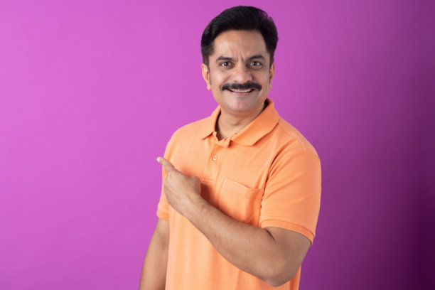 身穿橙色T恤的印度中年男子，孤立在紫色背景上的照片图片下载