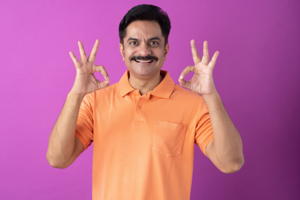 身穿橙色T恤的印度中年男子，孤立在紫色背景上的照片素材图片下载