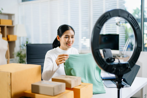 时尚博主概念，年轻亚洲女性在视频直播中卖衣服。创业小微企业，使用智能手机或平板电脑接收和查看信息。图片下载