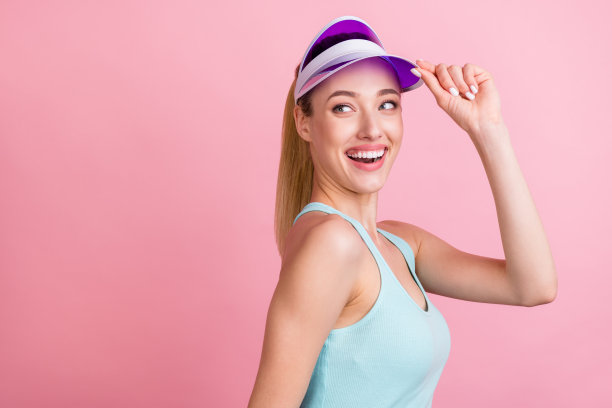 粉色背景上，一位戴着遮阳帽、穿着蓝色上衣的千禧一代金发女士的搞笑个人资料照片，她正望着空白处。图片下载