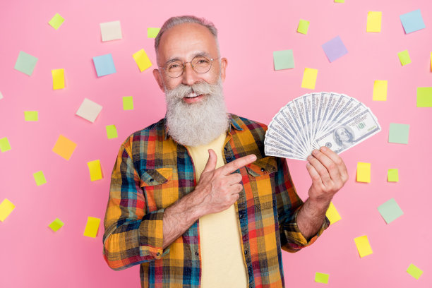 照片：一位穿着格子衬衫的幸运可爱的中年男子，在粉色贴纸的彩色背景上找到了绝佳的薪资解决方案。图片下载