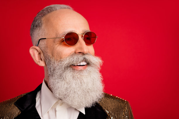 照片：迷人的、快乐的年轻男子戴着太阳镜，面带微笑，望向空白处，背景为红色图片下载