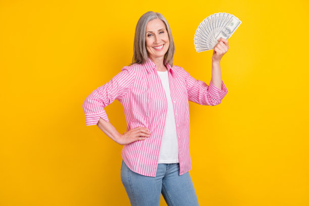 老年女性侧面头像，开心积极的笑容，富有，手持现金，孤立在黄色背景上图片下载