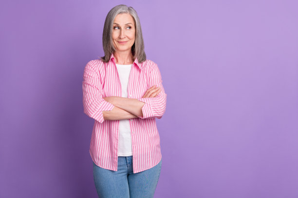 照片：一位年长的女商人带着快乐积极的微笑，双手交叉，眼神自信，有空白区域，孤立在紫色背景上图片下载
