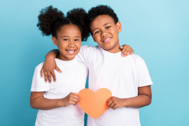 照片：两个非洲孩子快乐积极地微笑、拥抱、充满爱意，在蓝色背景上图片下载