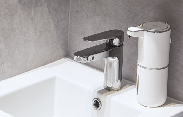 现代浴室白色水槽上的水龙头和自动皂液器图片下载