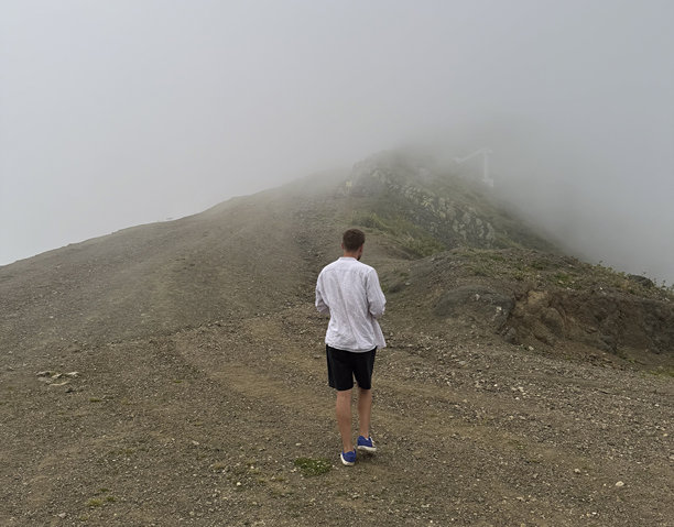 一个人走在崎岖的山路上，周围是浓雾弥漫。图片下载