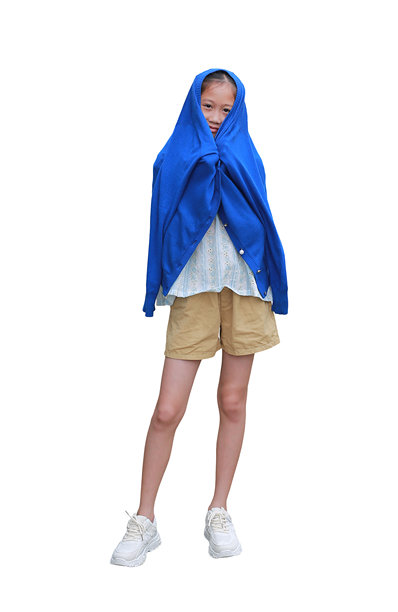 一个亚洲小女孩穿着休闲装，头上套着一件蓝色毛衣，独立于白色背景站立。图片为全长，包含抠图路径。图片下载