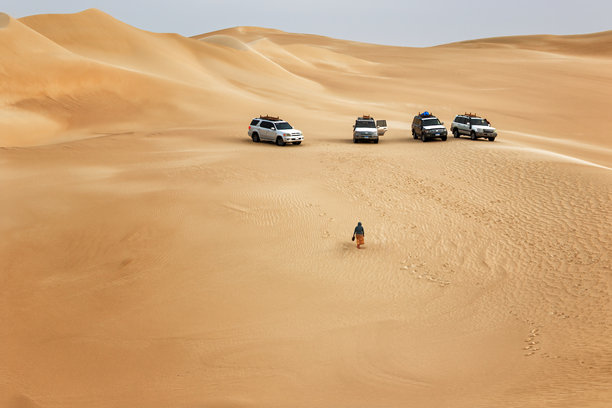 在埃及的锡瓦绿洲沙漠中，四辆越野车停在金色的沙丘上。图片下载