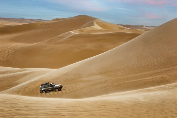 一辆越野车驰骋在埃及锡瓦绿洲沙漠的金黄沙丘上图片下载