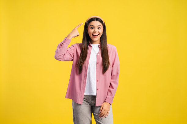 一位戴着时尚发带的兴奋的少女，她正笑着，灵光一闪，用手指着自己的头图片下载