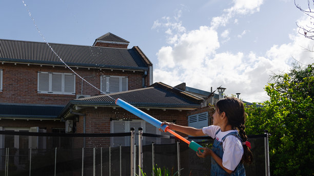 一个小女孩在后院玩水枪。图片下载
