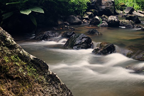 西爪哇热带雨林中，苔藓岩石和葱郁绿植环绕下的丝滑溪流长曝光照片图片下载