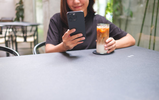 女子在咖啡馆里一边喝咖啡一边看手机的特写照片图片下载