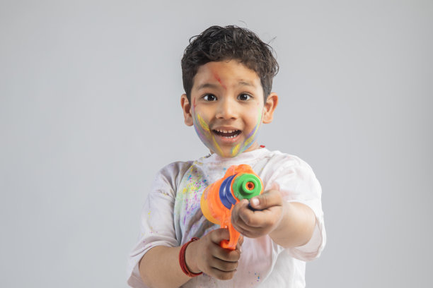 快乐的小男孩在白色背景上玩水枪图片下载