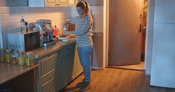 一位女士在温馨的居家厨房里，在一个玻璃碗中为制作鸡蛋牛奶煎蛋卷的混合物加盐。图片下载