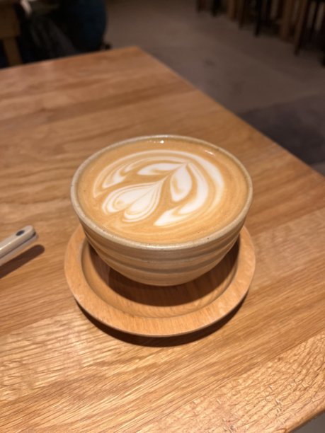 一杯精美的拿铁，浓郁的意式浓缩咖啡上覆盖着奶油般的拉花。这张图片非常适合咖啡相关的项目，捕捉了经典咖啡馆体验的温暖和诱人之处。图片下载