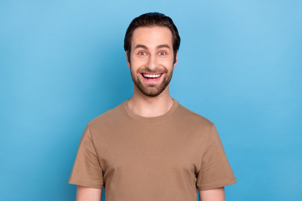 照片：一位穿着休闲棕色服装、自信迷人的年轻男子，背景是蓝色的纯色。图片下载