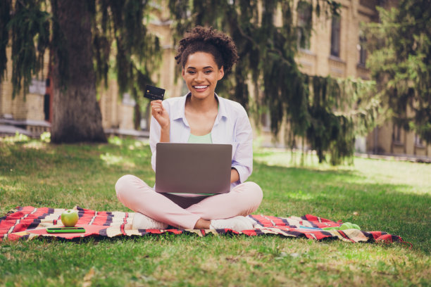 照片：年轻迷人的黑人女性，带着快乐积极的微笑，在公园户外一边走路一边用智能手机发短信聊天图片下载