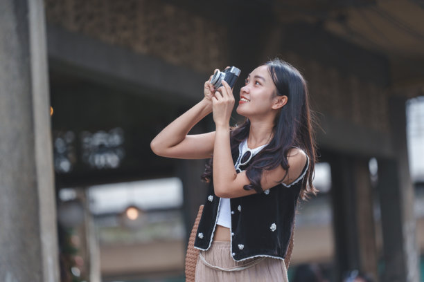 快乐的年轻亚洲游客用老式相机捕捉令人惊叹的城市建筑照片，全身心投入旅行体验，享受异国城市的活力氛围图片下载