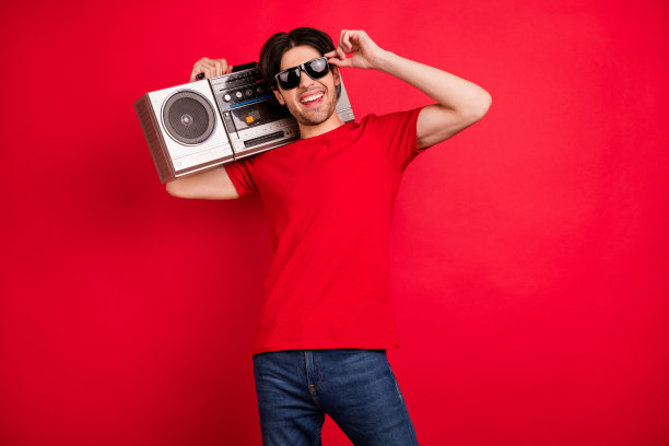 照片：一个笑容灿烂、聪明友善的男人，手托下巴，看向镜头，脸上带着微笑，身穿红色T恤，背景是孤立的红色。图片下载