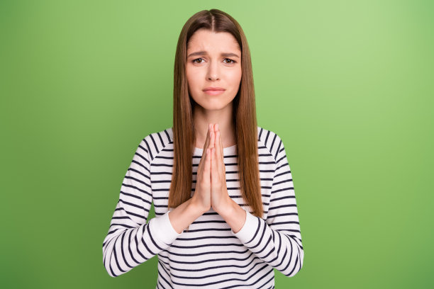 照片：年轻女子，表情不开心、悲伤、沮丧，恳求、祈祷，负面情绪，孤立于绿色背景上图片下载