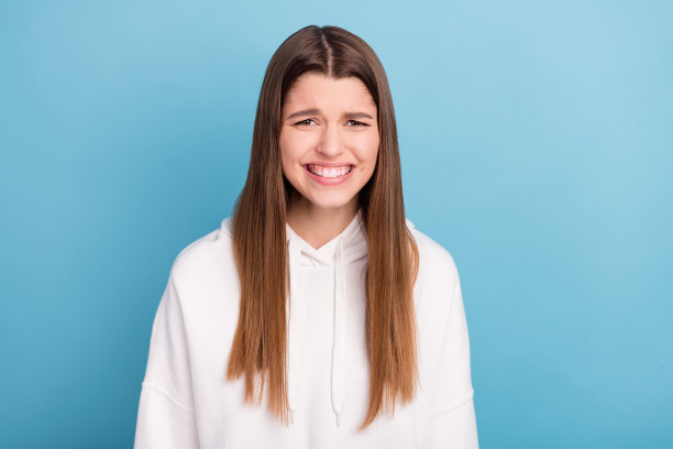 身穿运动服的女孩大笑的照片肖像，背景为粉蓝色，显得滑稽可爱图片下载