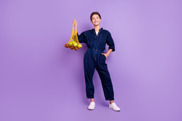 照片：一位震惊的千禧一代女士，留着短发，张着嘴，穿着牛仔衬衫，孤立在紫色背景上图片下载