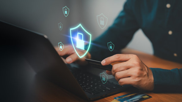 一个人拿着信用卡在笔记本电脑上打字，旁边有盾牌和挂锁图标。概念是网络安全、安全在线支付、数据保护、网上银行、欺诈预防和数字安全。图片下载