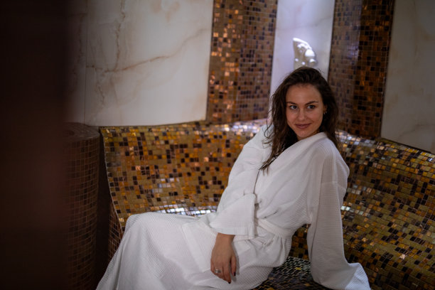 一位年轻女子在奢华水疗蒸汽房内穿着浴袍放松。素材图片图片下载