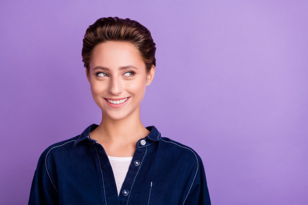 照片：一位惊讶的千禧一代女士，留着短发，张着嘴，穿着牛仔衬衫，孤立在紫色的背景上图片下载