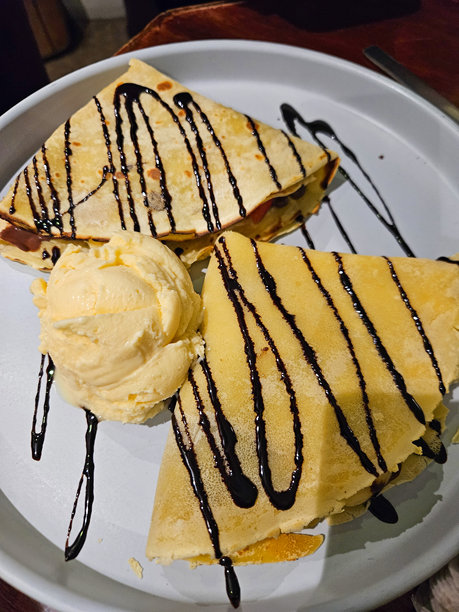盘子上盛着淋有巧克力糖浆和奶油香草冰淇淋的温热可丽饼图片下载