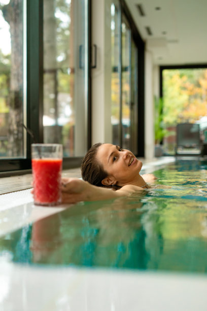 女性在室内泳池放松，享受清爽的冰沙饮品。素材图图片下载