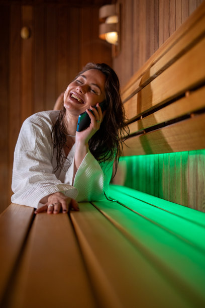 年轻女子在桑拿房里边接电话边大笑。素材图片图片下载
