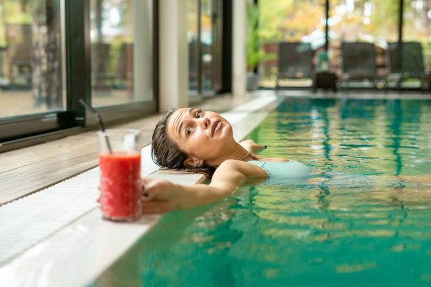 女子在泳池中放松，享用健康的冰沙饮品。素材图片图片下载