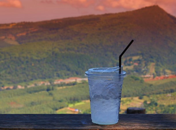 这张图片展示了在木桌上的一杯冷饮，背景是群山。图片下载