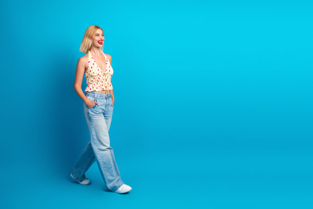 年轻女子身着休闲夏装，在蓝色影棚背景前微笑，用于时尚生活方式图库照片图片下载
