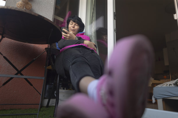 时尚博主在阳台上展示粉色木跟鞋，背景时尚有型图片下载