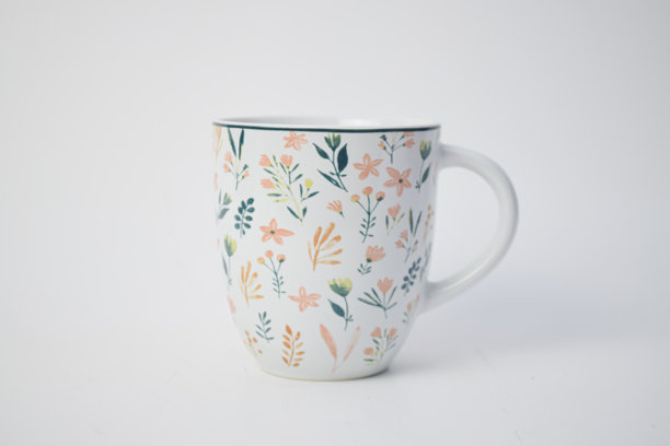 白色陶瓷咖啡杯，饰有色彩缤纷的手绘花卉和叶子图案，孤立在白色背景上。图片下载