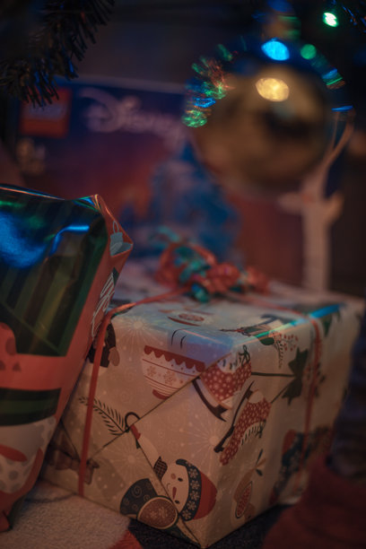 一张装饰过的圣诞树下摆放着包装好的礼物的照片，背景是圣诞和新年庆祝活动。这张图片传达了温暖、喜悦和神奇的节日气氛，非常适合季节性促销和节日设计。图片下载